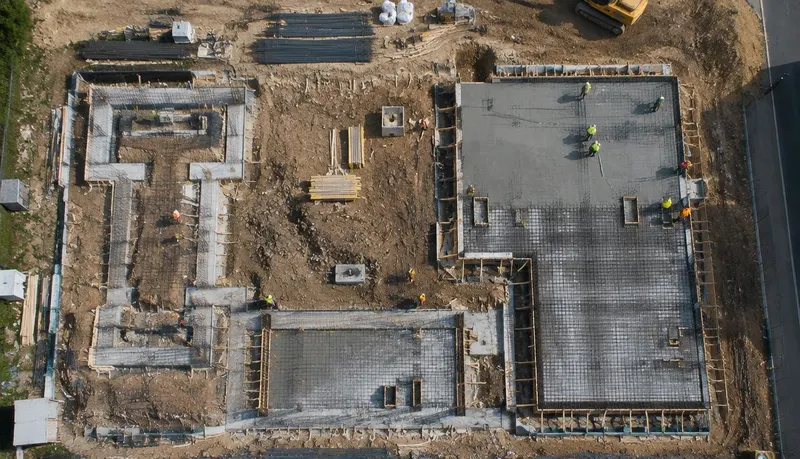 Vista aérea vertical de fundações e lajes em concretagem em um canteiro de obras