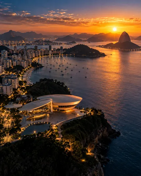 Vista aérea de orla ao pôr do sol com museu e baía